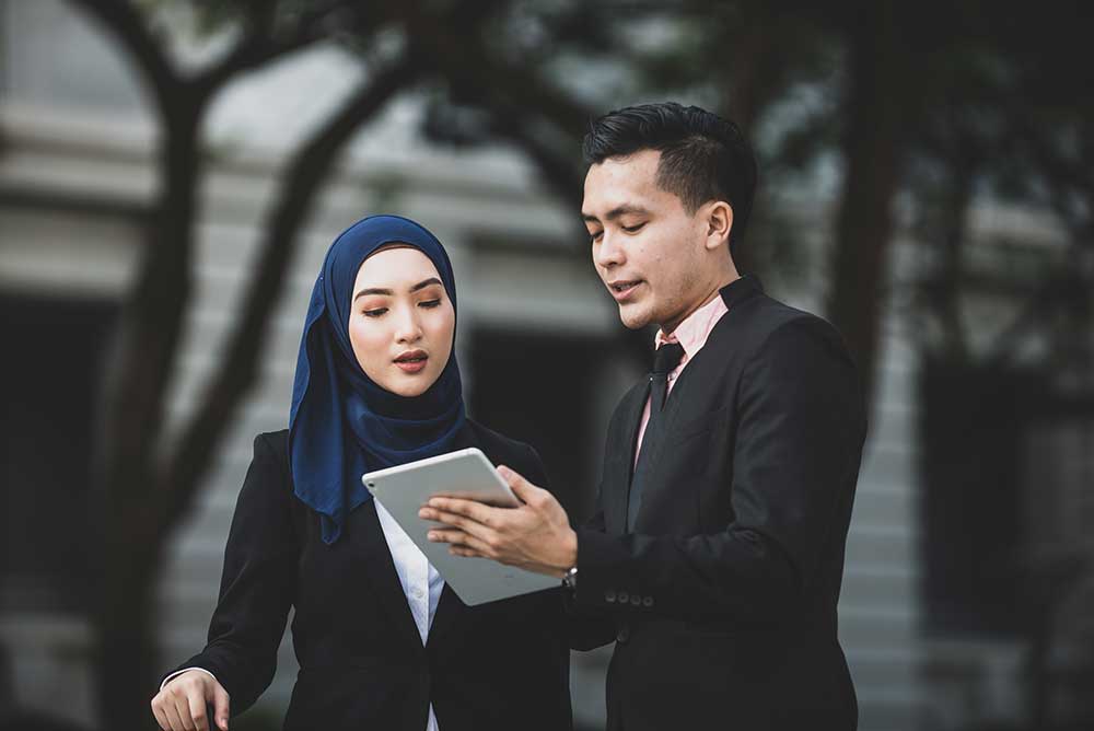 A middle aged female and male discussing business whilst using a computer