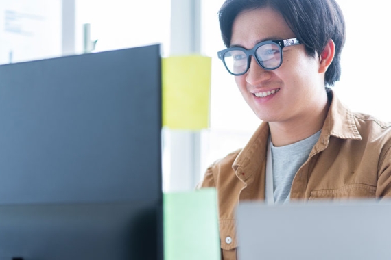 Young graduate male using laptop wearing glasses