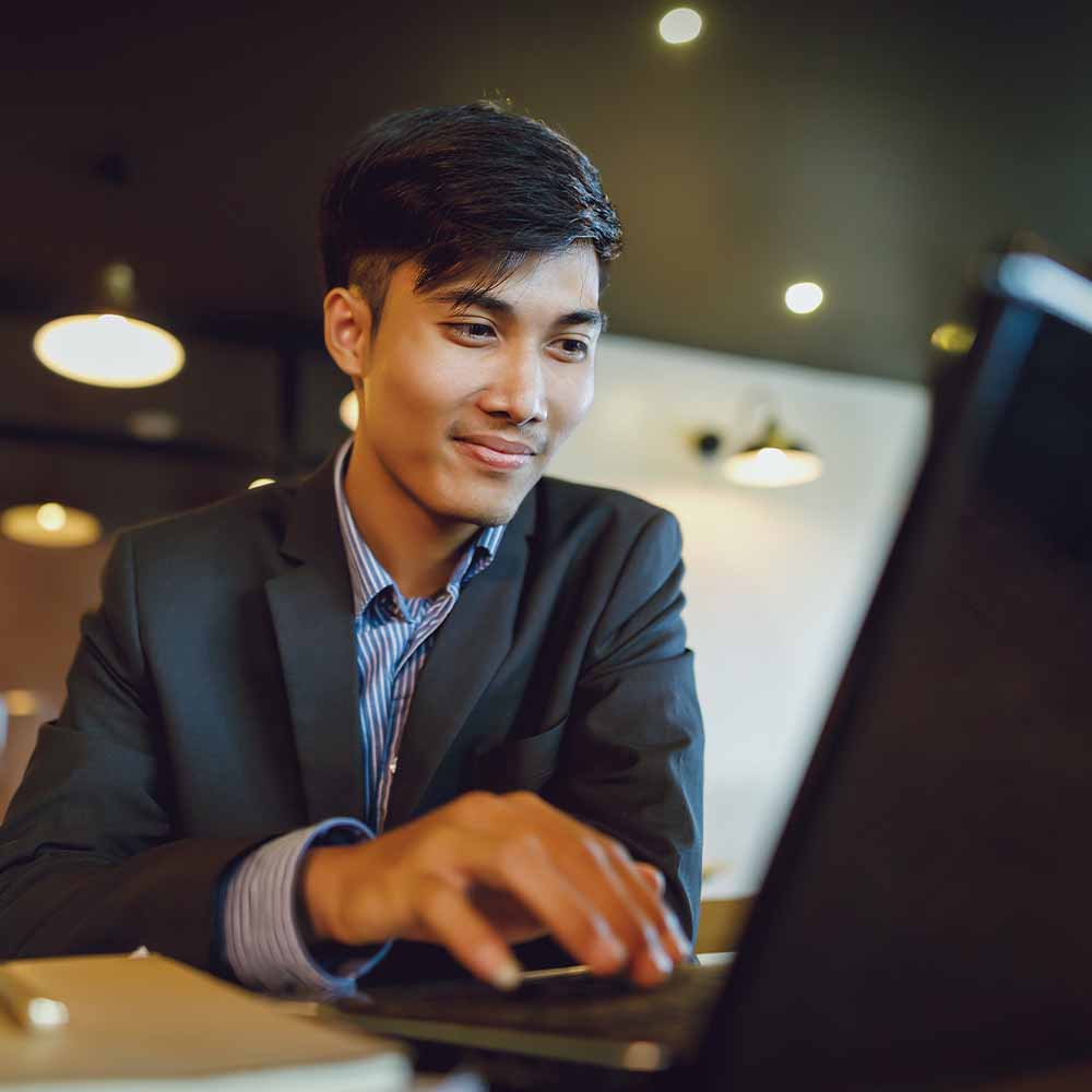 A young professional graduate in suit using a laptop
